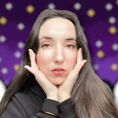 Photo de profil Spokinette, selfie mains tenant la tête en V sur un fond de ciel étoilé violet
